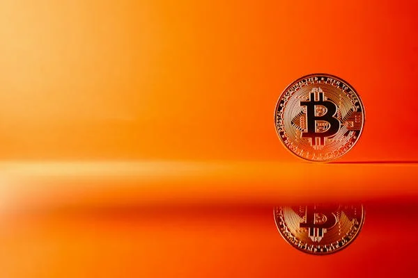 Bitcoin with reflection on orange surface