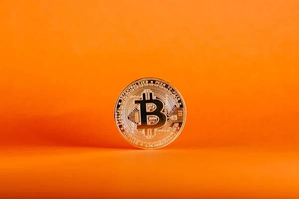 Single bitcoin on orange background